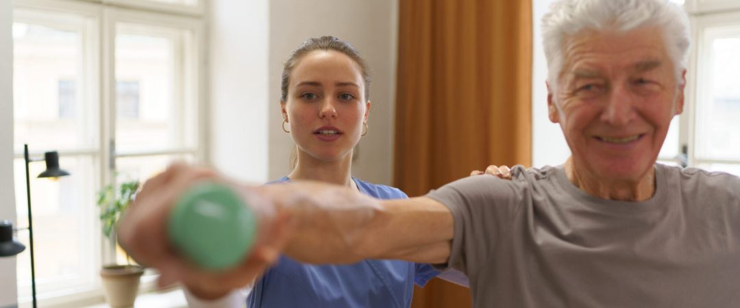 Young nurse doing exercise with senior man in his home.