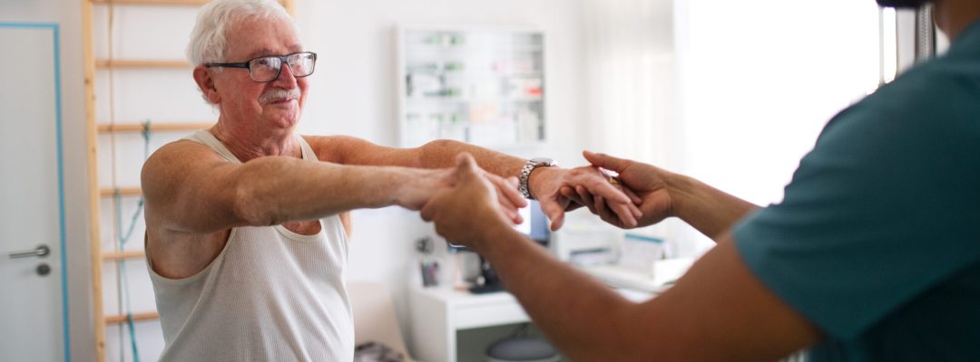 A young physiotherapist exercising with senior patient in a physic room.